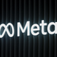 A glowing Meta logo is displayed in front of a black wall.